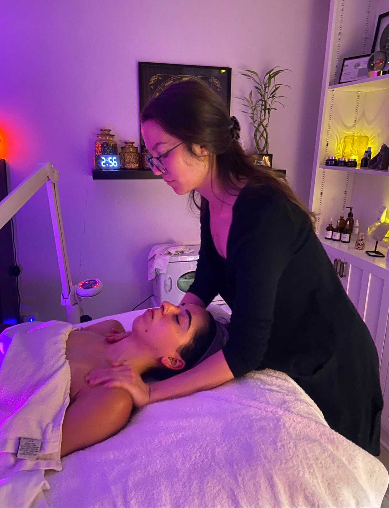 Massage therapist giving a relaxing shoulder massage in a calm, softly lit room.