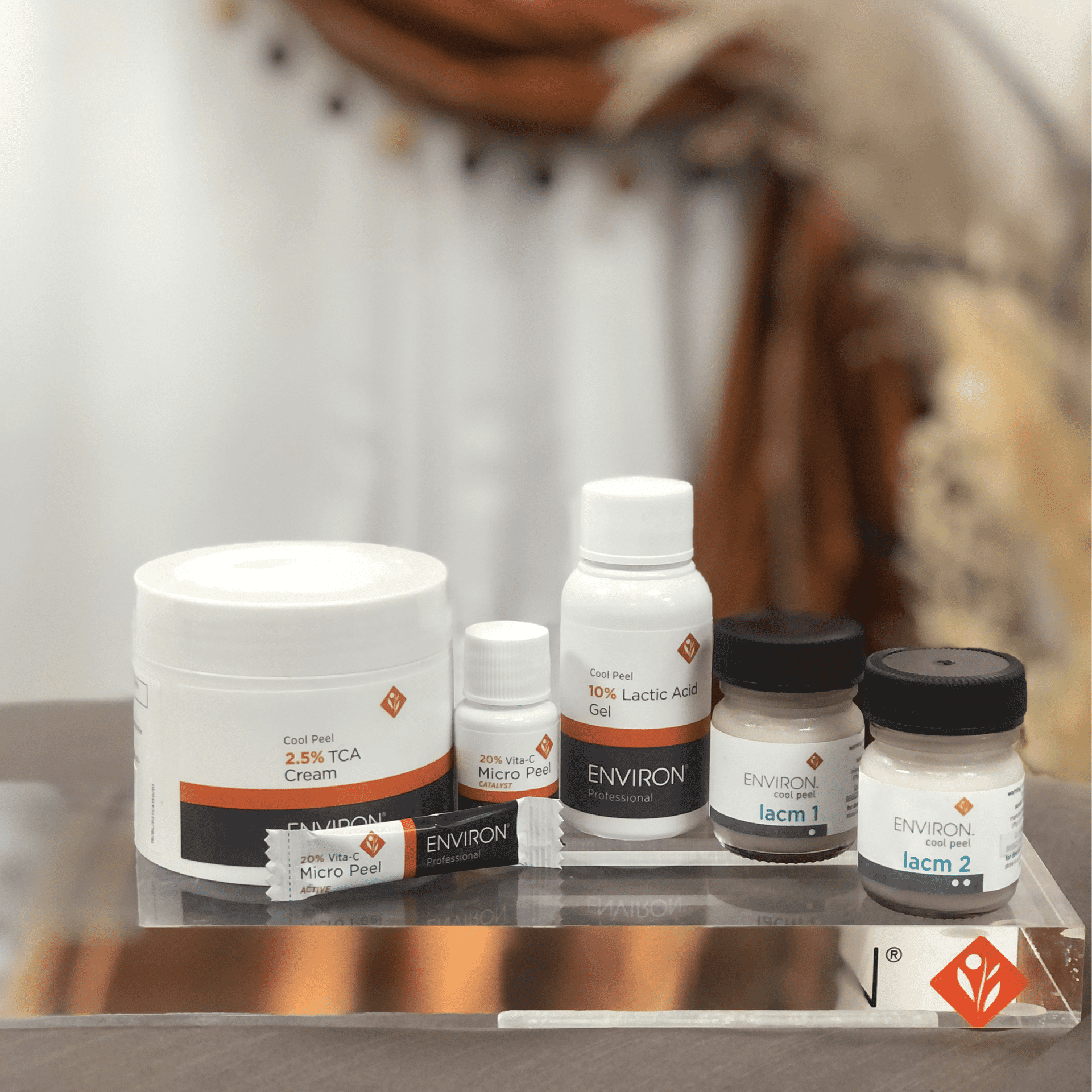 Skincare products assortment on a clear display stand with a blurred background.